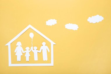Sarı arka plan üzerinde bulutlar ve ev ile Kağıt aile figürleri