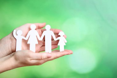 Family figures in female hands on green background clipart