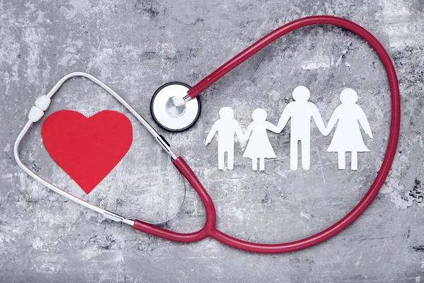 Семейные фигуры с красным сердцем и стетоскопом на сером фоне — стоковое фото