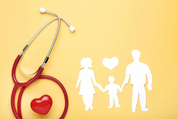 Familienfiguren mit rotem Herz und Stethoskop auf gelbem Hintergrund — Stockfoto