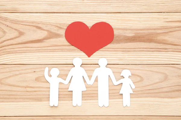 Figuras familiares con corazón rojo sobre mesa de madera marrón —  Fotos de Stock