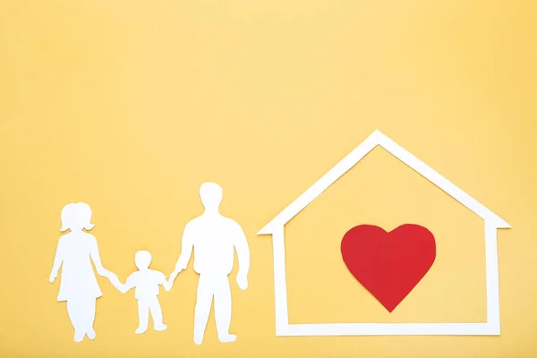 Figure di famiglia e casa con cuore rosso su sfondo giallo — Foto Stock