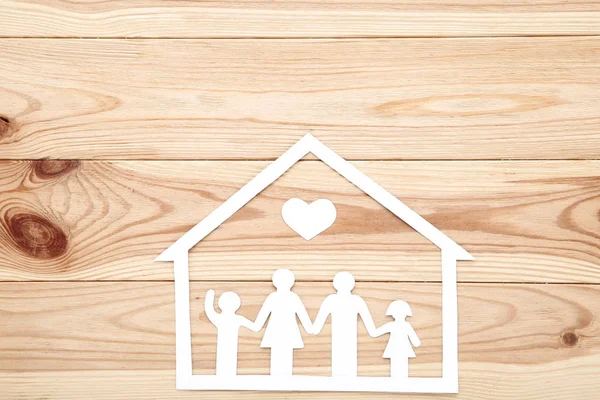 Figure di famiglia di carta con cuore e casa su tavolo di legno — Foto Stock