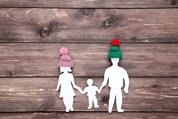 Figuras familiares de papel con sombreros pequeños sobre mesa de madera marrón — Foto de Stock
