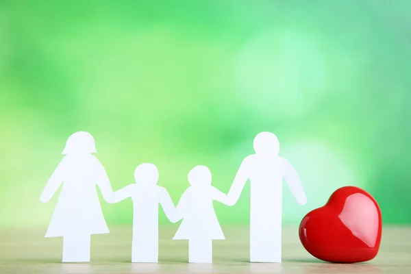 Семейные фигуры с красным сердцем на зеленом фоне — стоковое фото