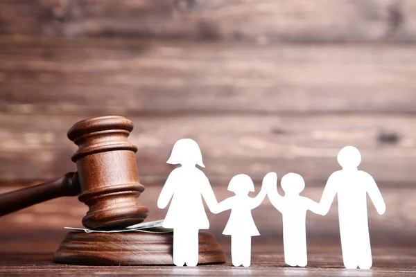 Family figures with gavel on brown wooden table — Stock Photo, Image