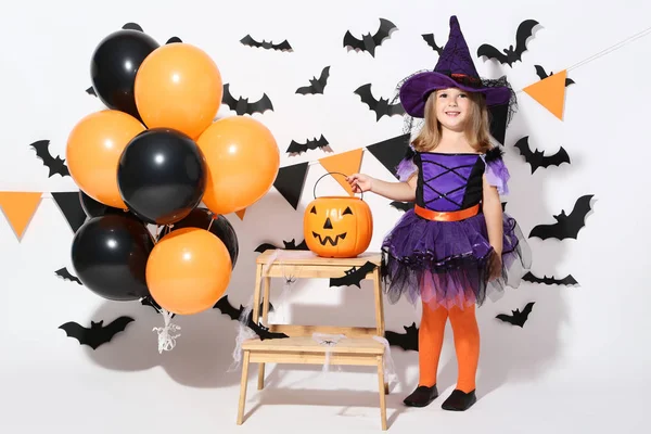 Giovane ragazza in costume di Halloween con palloncini e secchio di zucca — Foto Stock