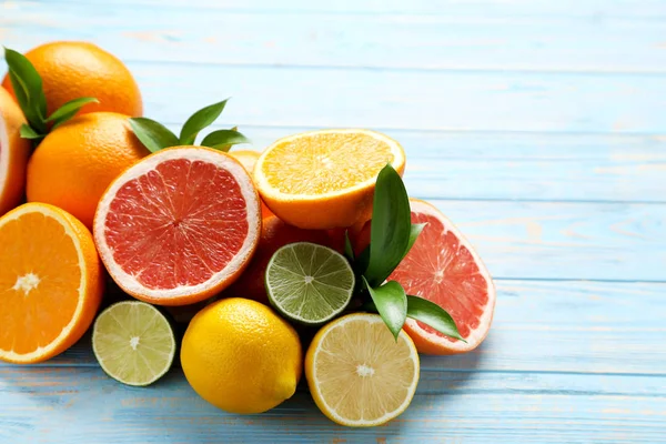 Mavi ahşap masada yeşil yapraklı narenciye