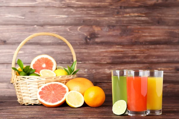 Citrus juice in glasses with fruits on brown wooden table — Stock Photo, Image