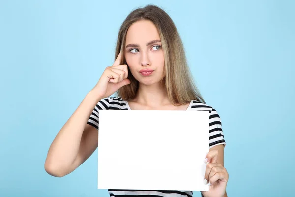 Hermosa mujer joven sosteniendo tablero blanco en blanco sobre fondo azul —  Fotos de Stock