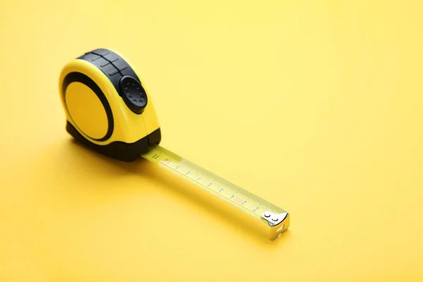 Строительная рулетка на желтом фоне — стоковое фото