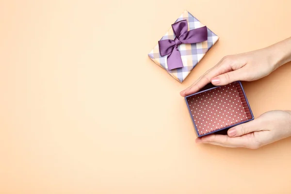 Female hands holding gift box on beige background — Stock Photo, Image