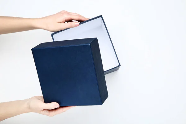 Manos femeninas abriendo caja de regalo azul sobre fondo blanco — Foto de Stock