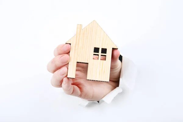 Рука держа деревянный дом модель из белой рваной бумаги — стоковое фото