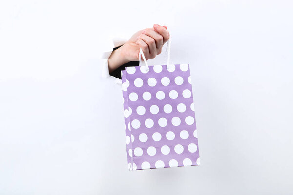 Рука держит пакет из белой рваной бумаги
