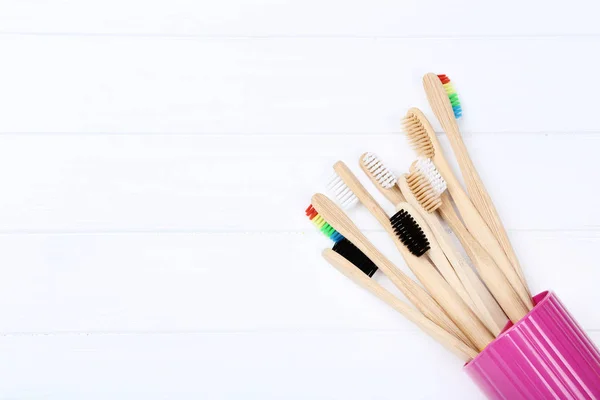 Bambu tandborstar i korg på vitt träbord — Stockfoto