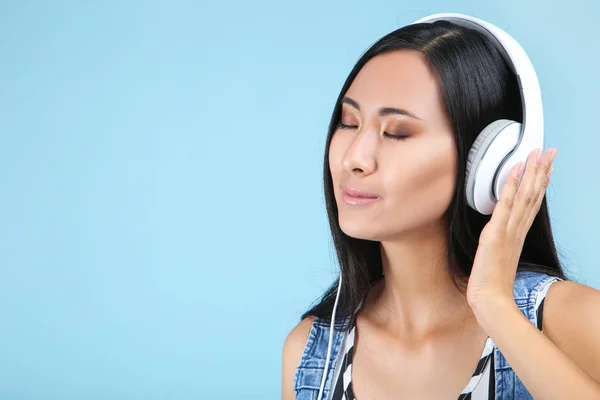 Mooie vrouw met koptelefoon op blauwe achtergrond — Stockfoto