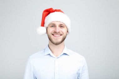 Gri arka planda noel baba şapkalı genç adamın portresi