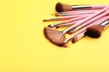Sarı arkaplanda makyaj fırçaları
