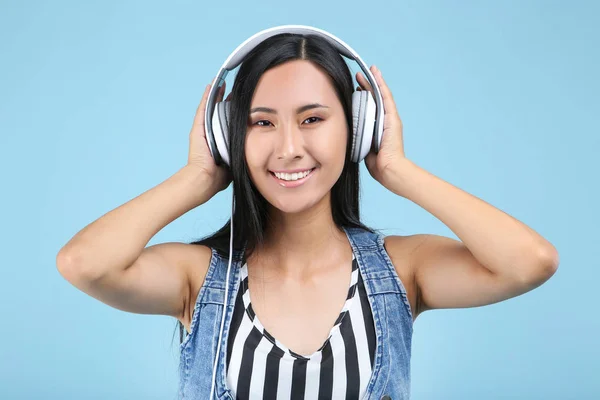 Mooie vrouw met koptelefoon op blauwe achtergrond — Stockfoto