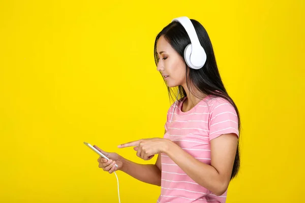 Belle femme avec casque et smartphone sur fond jaune — Photo