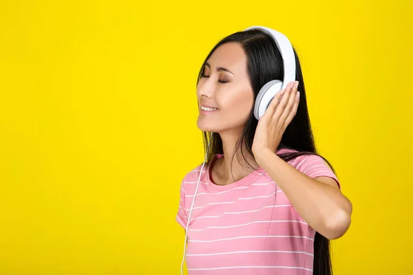 Belle femme avec écouteurs sur fond jaune — Photo