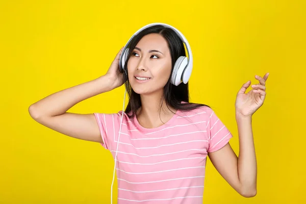 Mooie vrouw met koptelefoon op gele achtergrond — Stockfoto