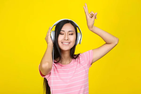 Mooie vrouw met koptelefoon op gele achtergrond — Stockfoto