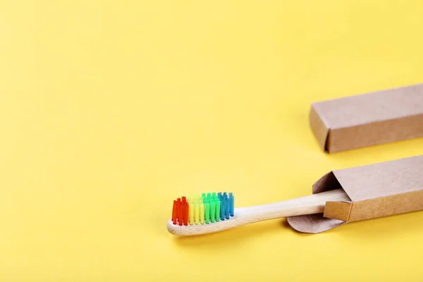 Bamboo toothbrush with paper case on yellow background — Stock Photo, Image