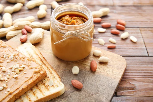 Erdnussbutter mit Brot und Nüssen auf Holztisch — Stockfoto
