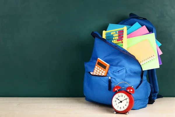 Batoh se školními potřebami na zeleném pozadí — Stock fotografie