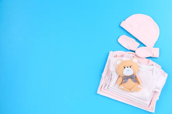 Bayi pakaian dengan mainan beruang lembut di latar belakang biru — Stok Foto