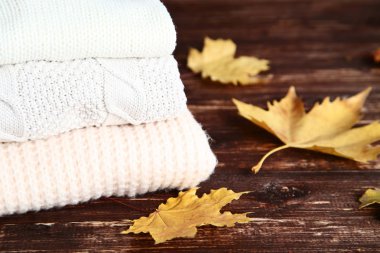 Ahşap masa üzerinde akçaağaç yaprağı ile katlanmış kazak Yığını