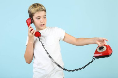 Mavi arka planda yakışıklı ve telefon ile genç çocuk