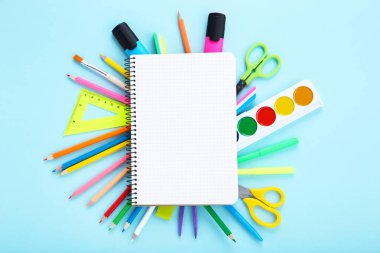 Farklı okul malzemeleri ve mavi backg üzerinde kağıt boş levha