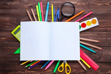 Kahverengi ahşap masa üzerinde açılan defter ile okul malzemeleri