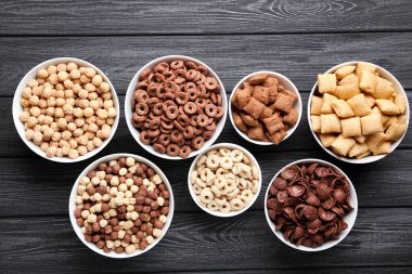 Siyah ahşap masadaki kaselerde çeşitli mısır gevrekleri