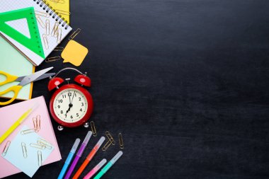 Kara tahta üzerinde çalar saat ile farklı okul malzemeleri