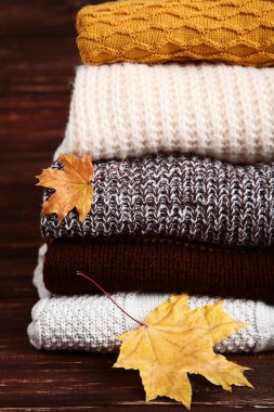 Ahşap masa üzerinde akçaağaç yaprağı ile katlanmış kazak Yığını