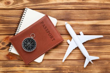 Kahverengi ahşap üzerinde pasaport, not defteri ve pusula ile Uçak modeli