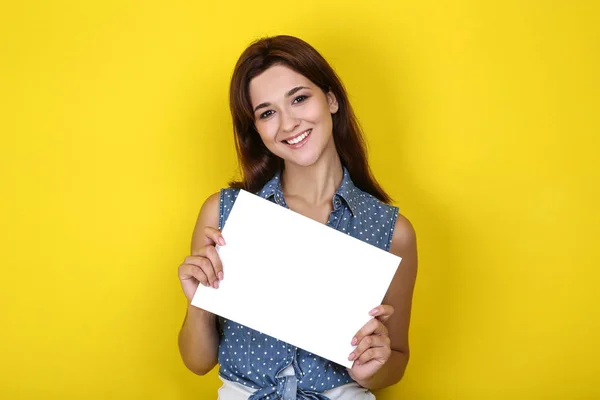 Giovane donna con foglio bianco su sfondo giallo — Foto Stock