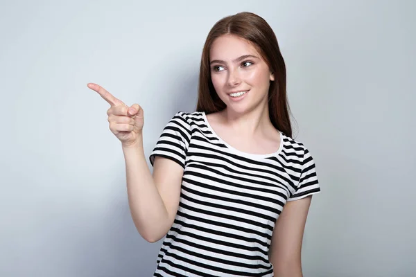Jonge vrouw in gestreepte t-shirt op grijze achtergrond — Stockfoto