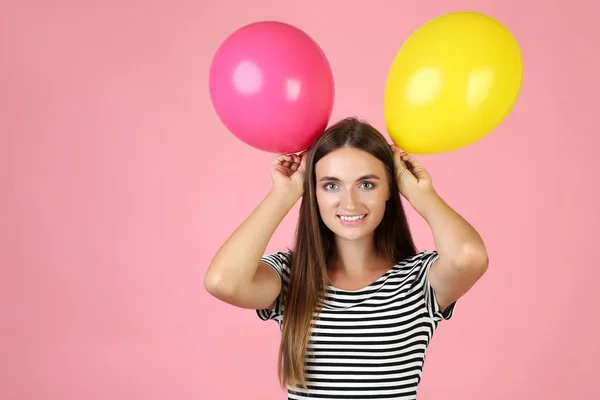 Giovane donna con palloncini colorati su sfondo rosa — Foto Stock