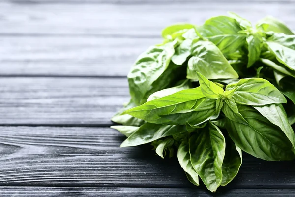 Green basil leafs on black wooden table — Stock Photo, Image