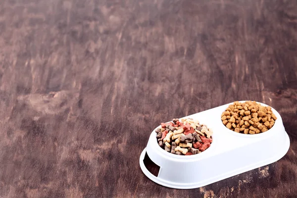 Сухой корм для домашних животных в мисках на коричневом деревянном столе — стоковое фото