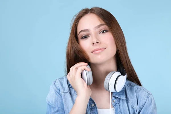 Jonge mooie vrouw met koptelefoon op blauwe achtergrond — Stockfoto