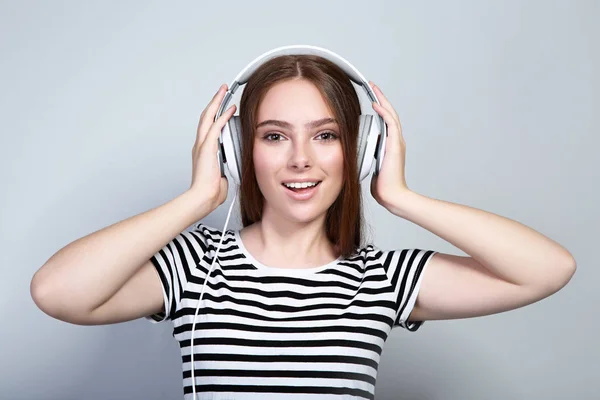 Mujer hermosa joven con auriculares sobre fondo gris — Foto de Stock