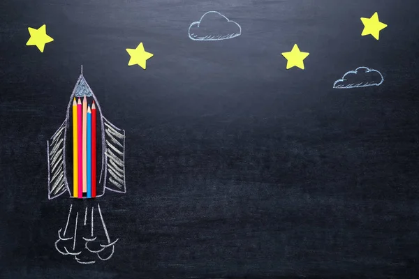 Малюнок ракети на дошці з різнокольоровими олівцями та папером sta — стокове фото