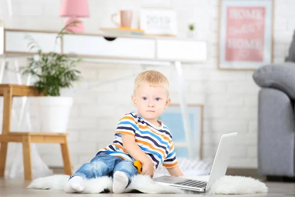 Маленький хлопчик з портативним комп'ютером сидить на білому килимі вдома — стокове фото