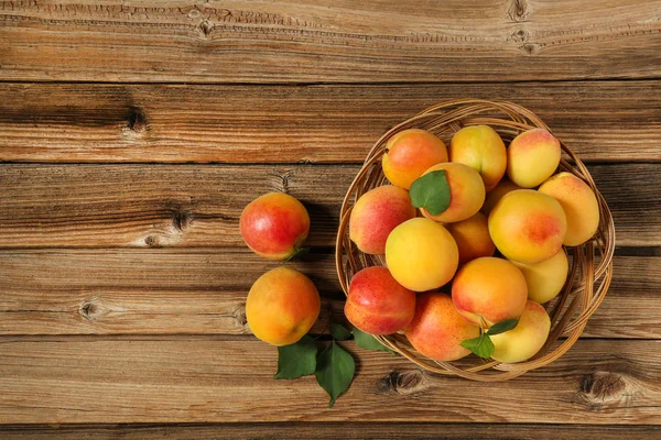 Sweet apricots in basket on brown wooden table